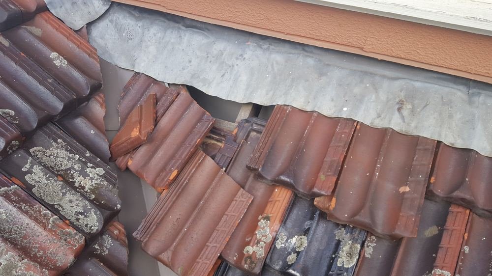 Broken roof tiles at a flashing junction causing a roof leak